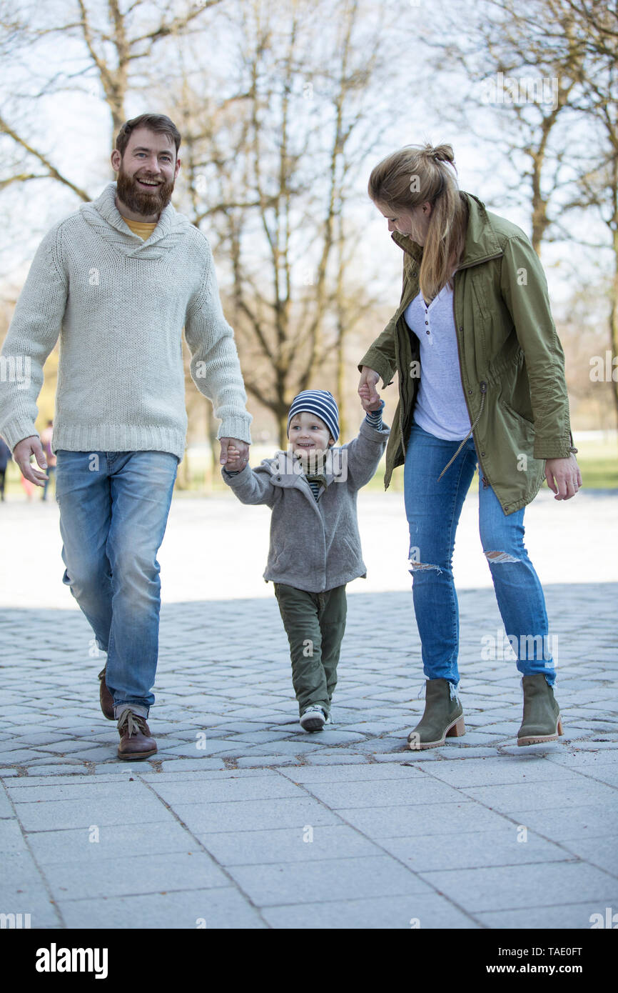 Happy parents walking hand in hand with son Stock Photo
