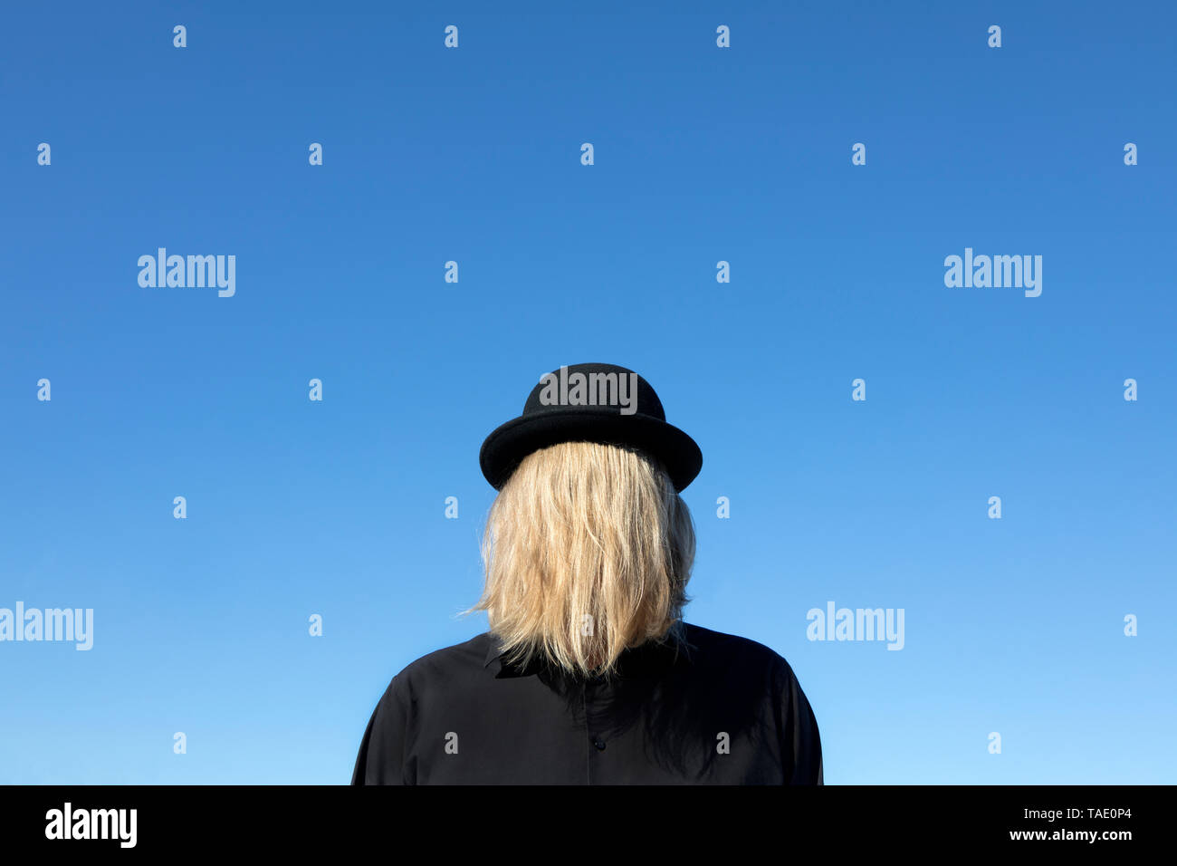 Blond hair covering man's face wearing bowler hat Stock Photo