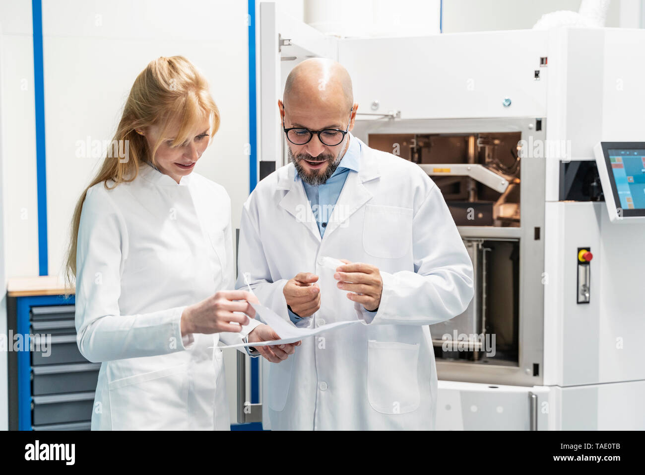 Two technicians wearing lab coats discussing plan Stock Photo