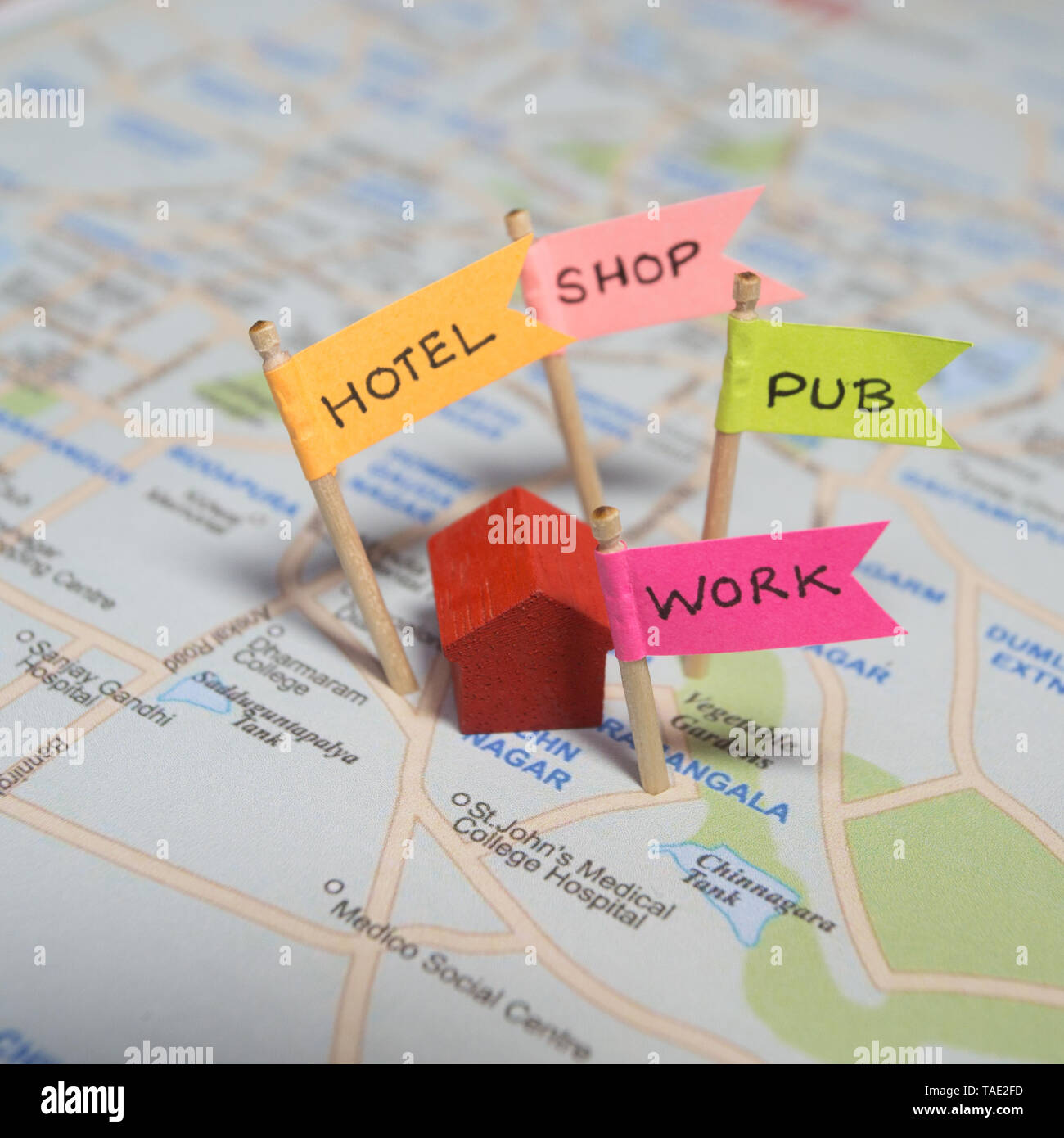 A small miniature house on a map with pins for work, hotel, shop and pub Stock Photo