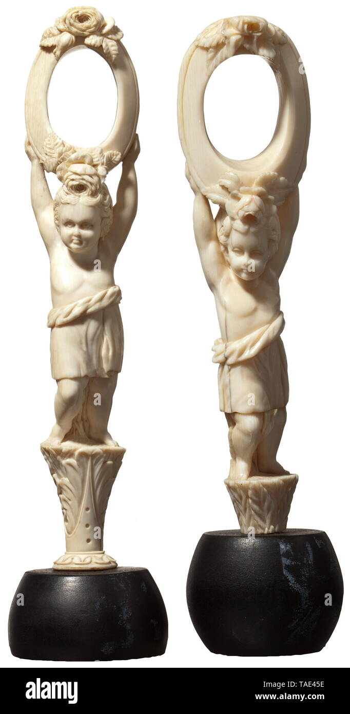A pair of ivory sculptures, 19th century Slightly differing, three-dimensional figures, each one standing on a florally carved, tapered base and with an oval ring on its head decorated with roses in relief. Later, ebonised wooden bases. Presumably used as napkin holders or for similar purposes. Total height 19 and 19.5 cm. historic, historical, handicrafts, handcraft, craft, object, objects, stills, clipping, clippings, cut out, cut-out, cut-outs, 19th century, Additional-Rights-Clearance-Info-Not-Available Stock Photo