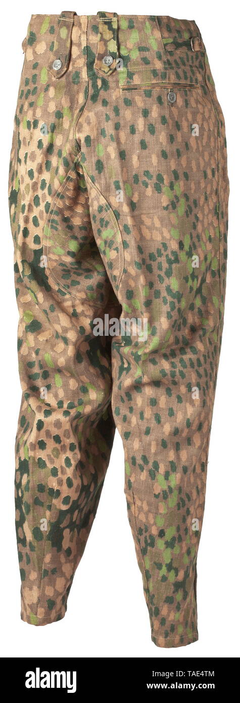 A pair of camouflage field trousers M 44 of the Waffen-SS depot piece from a late production series Drill cloth imprinted in pea pattern camouflage on one side, with sheet metal buttons. Reverse raised waist with four belt loops also usable for suspenders attachment, covered fly without waist button, superimposed fob pocket, both slanted front pockets and the straight hip pocket each with button closure, wedge-shaped leg terminals without securing straps. Pocket sacks and inner liner of olive-brown cotton (remnants from army tropical clothing?) with size- and maker stamping, Editorial-Use-Only Stock Photo