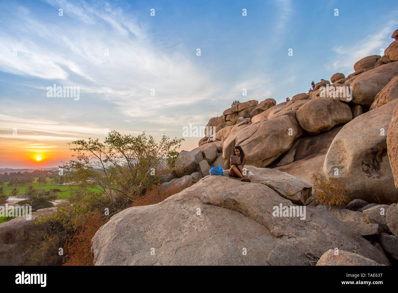 Tourists sitting on a sunset lookout spot in Hampi, India Stock Photo