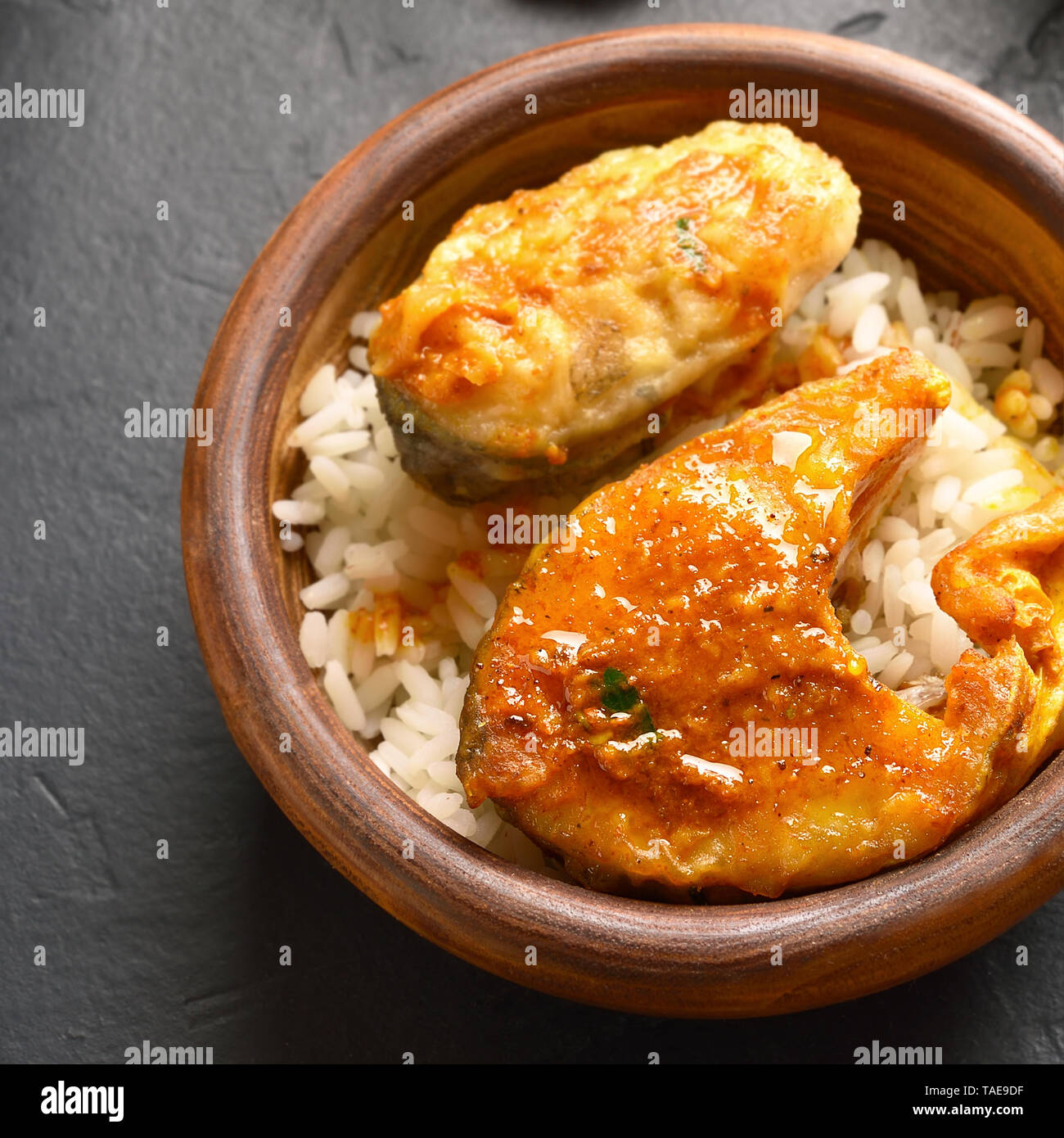 Close Up Of Fish Curry With Rice In Wooden Bowl On Black Stone