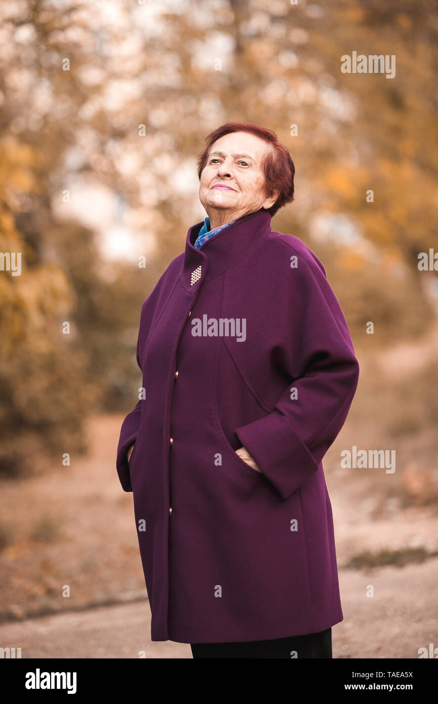 Senior woman 70-75 year old wearing winter jacket outdoors. Looking away. Stock Photo