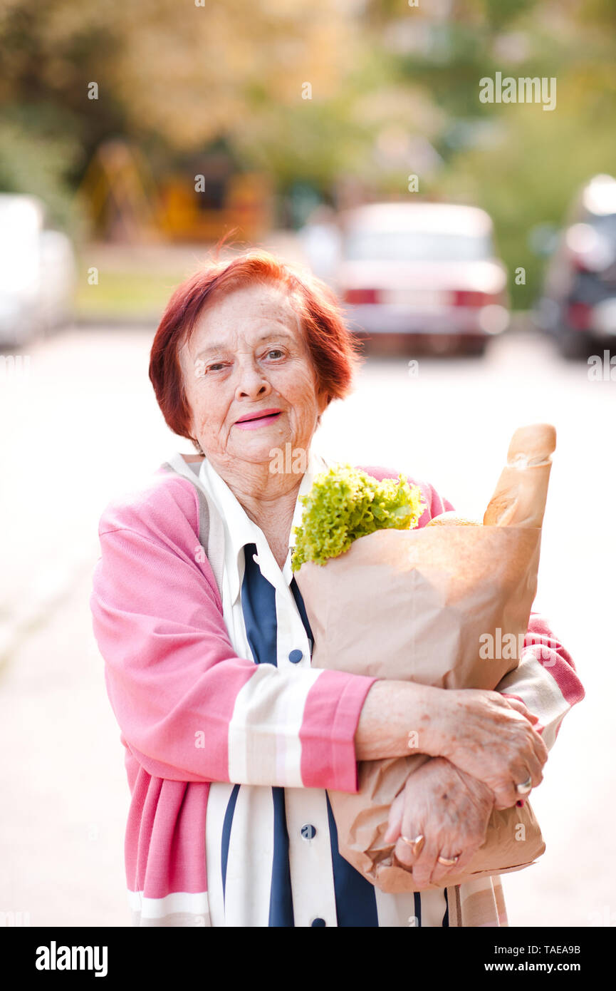Laughing senior woman 7080 year old holding paper bag with food