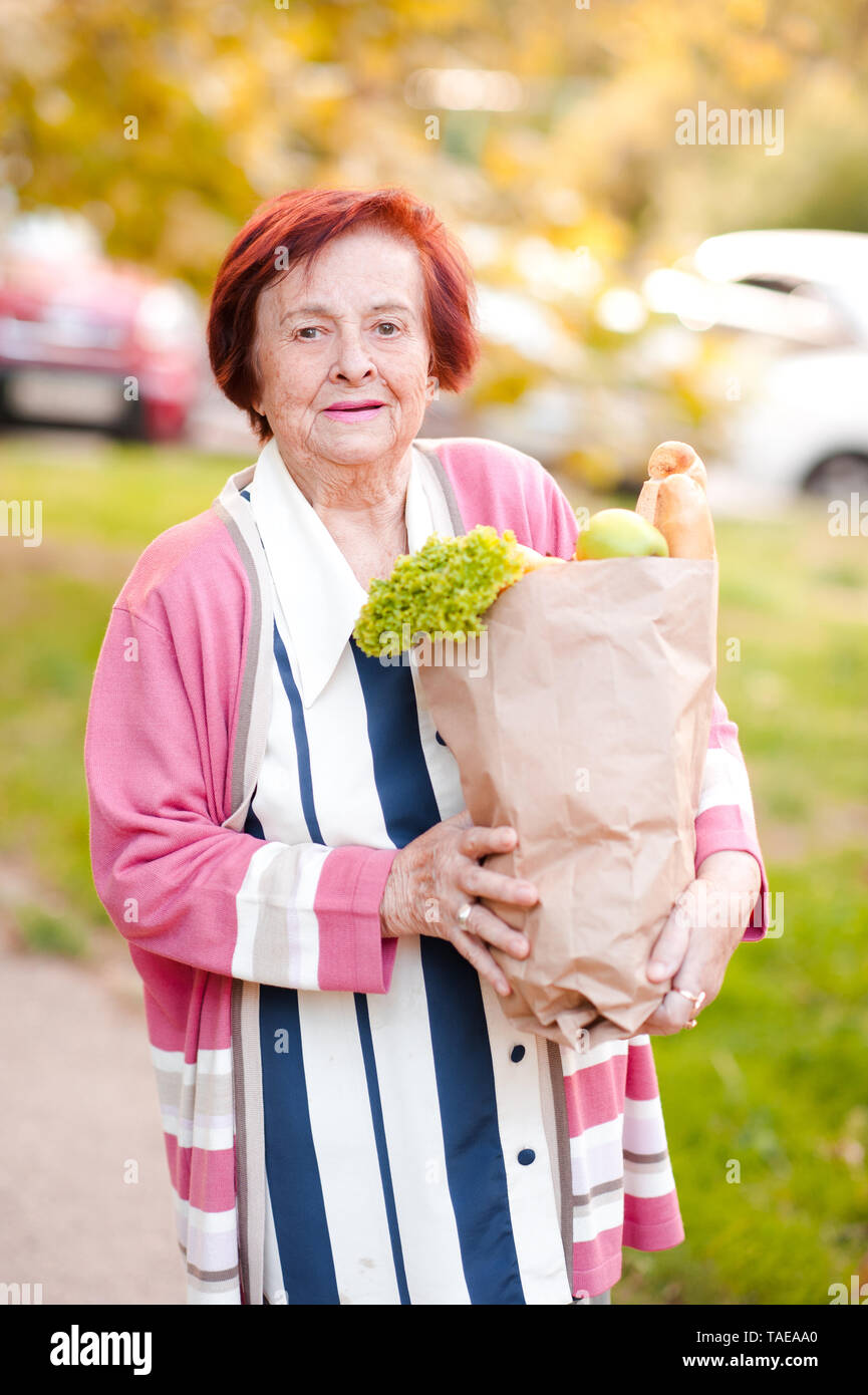Smiling senior woman 7080 year old holding paper bag with products