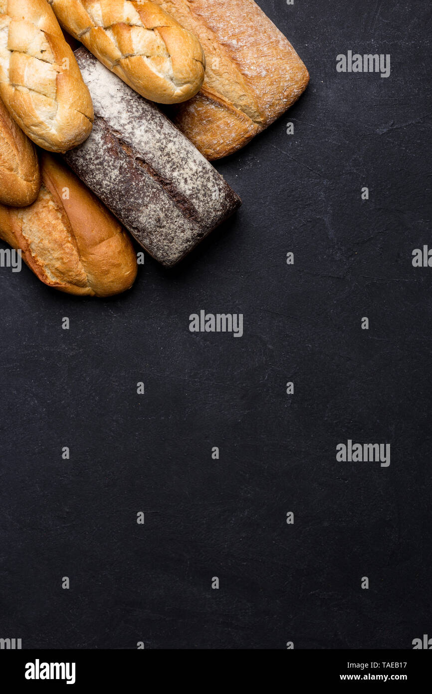 Mixed variety of breads on dark table. Top view with copy space for text Stock Photo