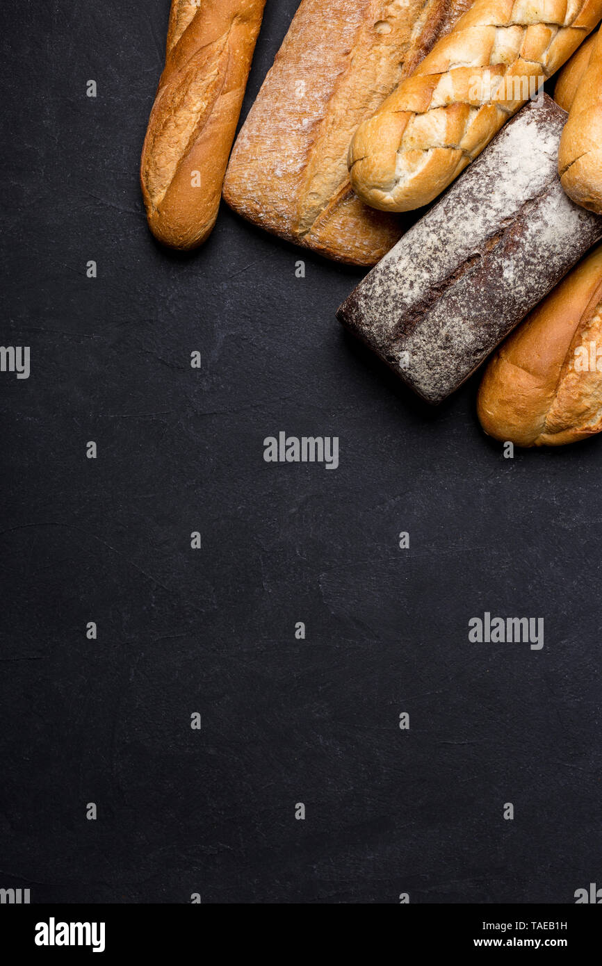 Variety of grain breads on black background. Flat lay, top view with free space for text Stock Photo