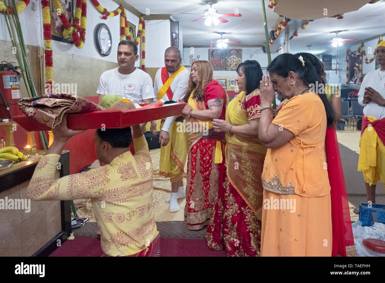 At his mother's thanksgiving service a young Hindu man brings offerings to the deities at a temple in Ozone Park, Queens, New York City. Stock Photo