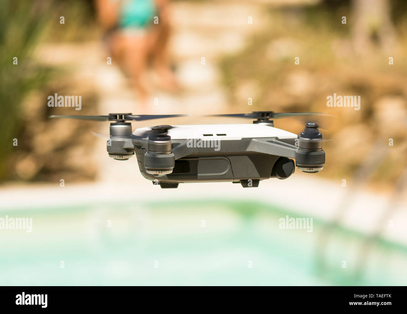 Drone copter, DJI Spark, flying next to pool, with high resolution digital camera, hovering in sky. Stock Photo