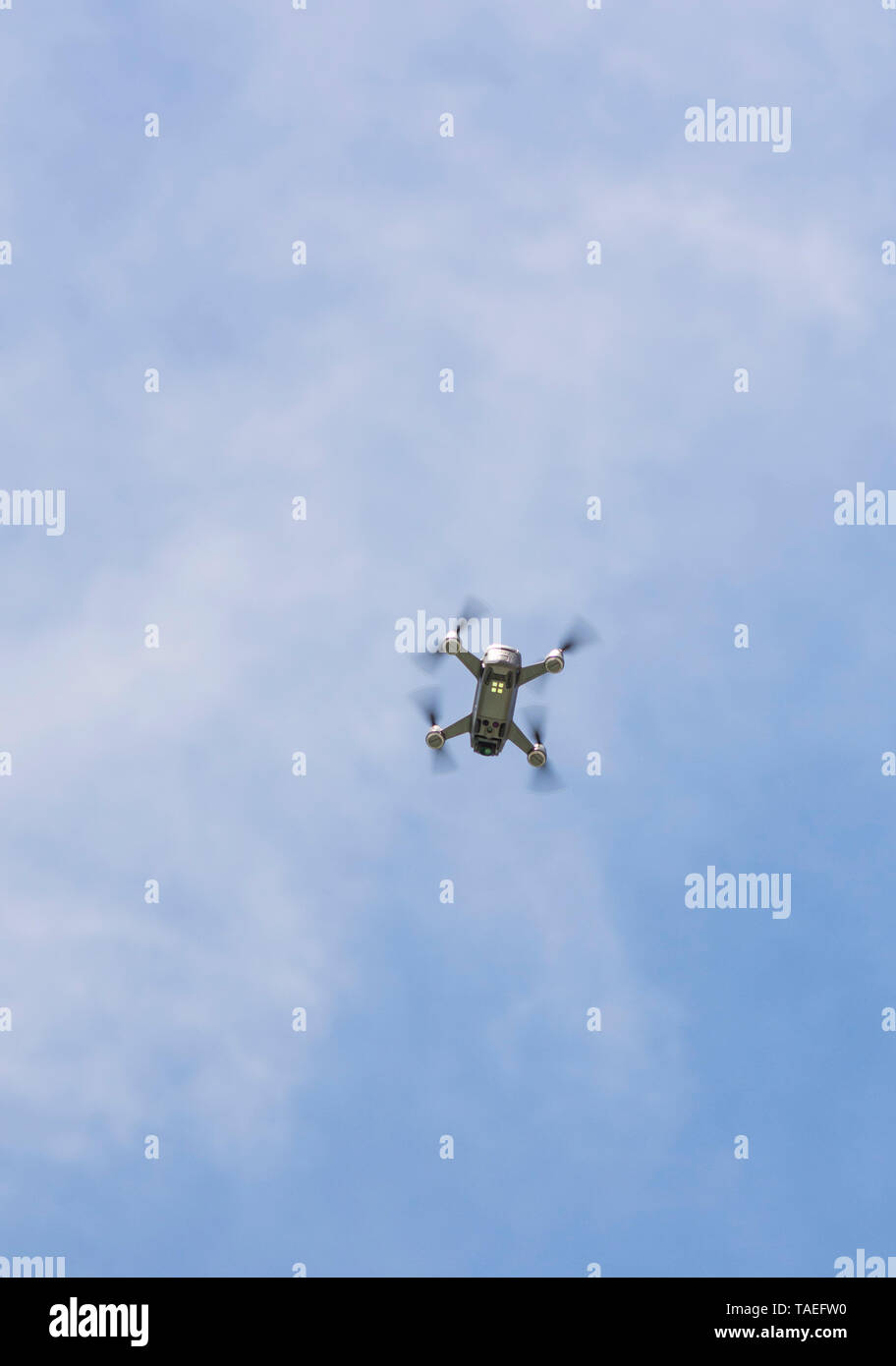 Drone copter, DJI Spark, flying with high resolution digital camera, hovering high in sky. Stock Photo