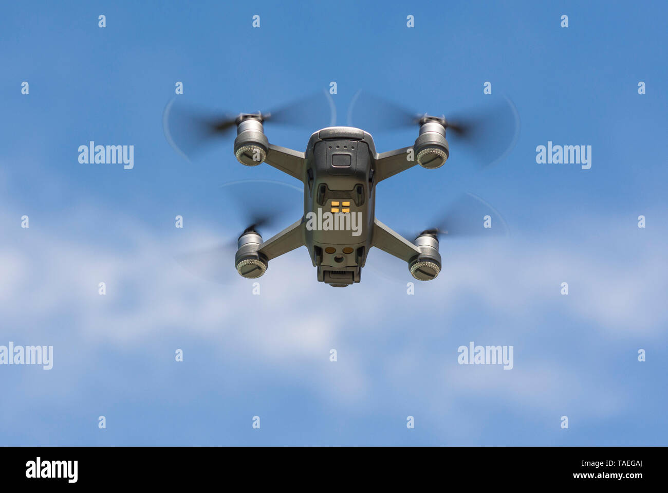 Drone copter, DJI Spark, flying with high resolution digital camera, hovering in sky. Stock Photo