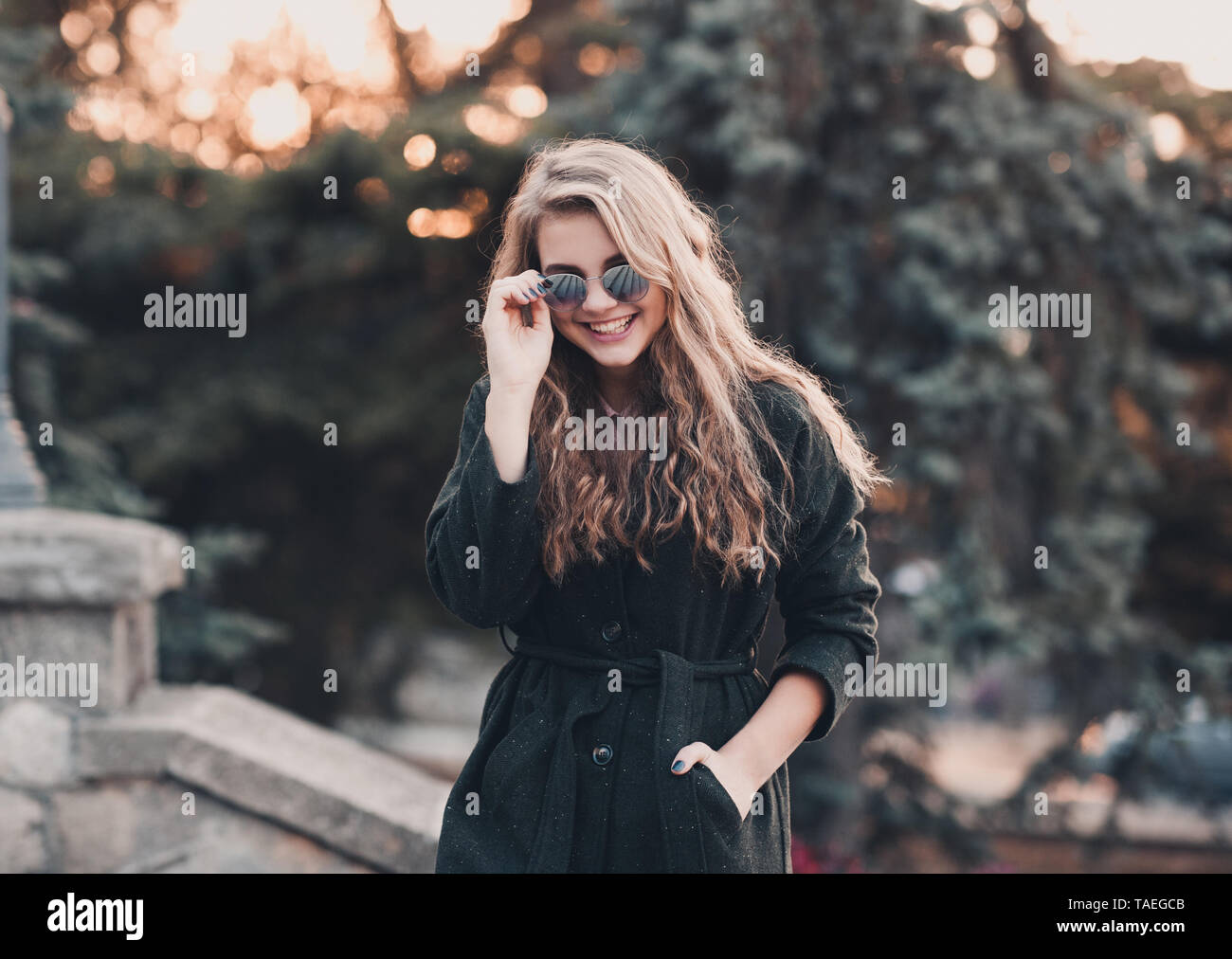 Beautiful teen girl 14-15 year old wearing stylish clothes sitting  outdoors. Looking at camera. Autumn season. Stock Photo