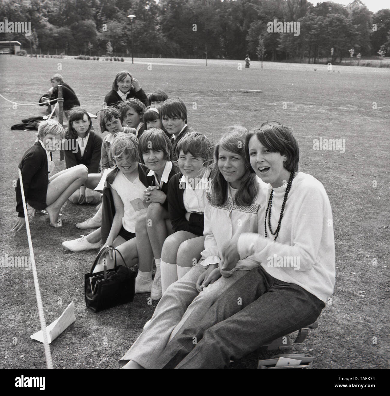 1967, historical, group of excited secondary school children sitting together outside in a field during a school sports day, England, UK. Stock Photo