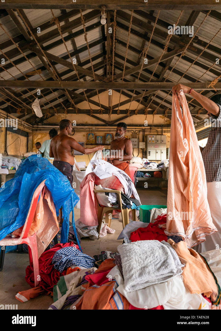 Vertical view of dhobi wallahs folding up clean clothes in India. Stock Photo