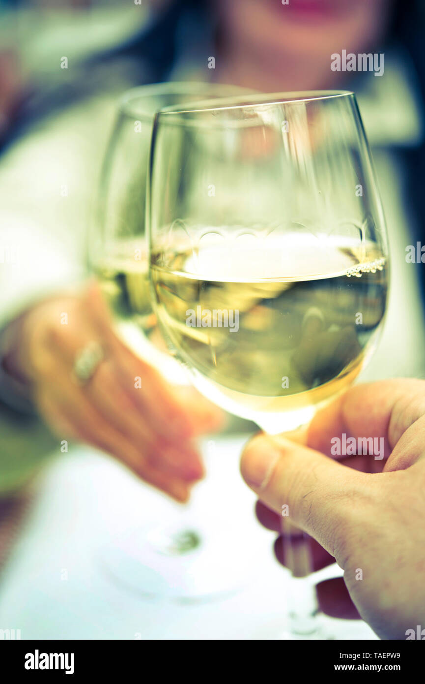 Two glasses of white wine clinking Stock Photo