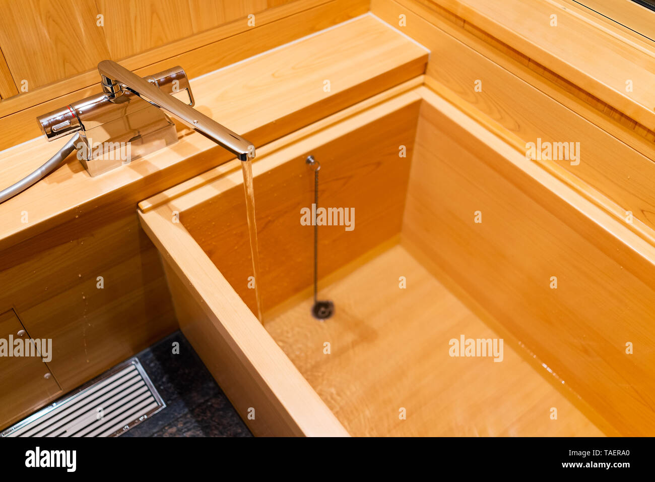 New clean cypress bathtub wooden traditional Japanese tub in home house or onsen hotel bathroom interior with nobody and running water in Japan Stock Photo