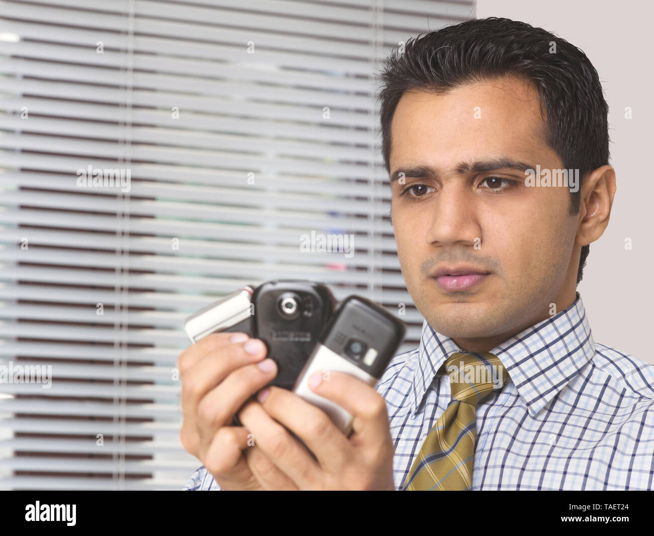 MAN HOLDING MULTIPLE MOBILE PHONES IN HIS HANDS Stock Photo