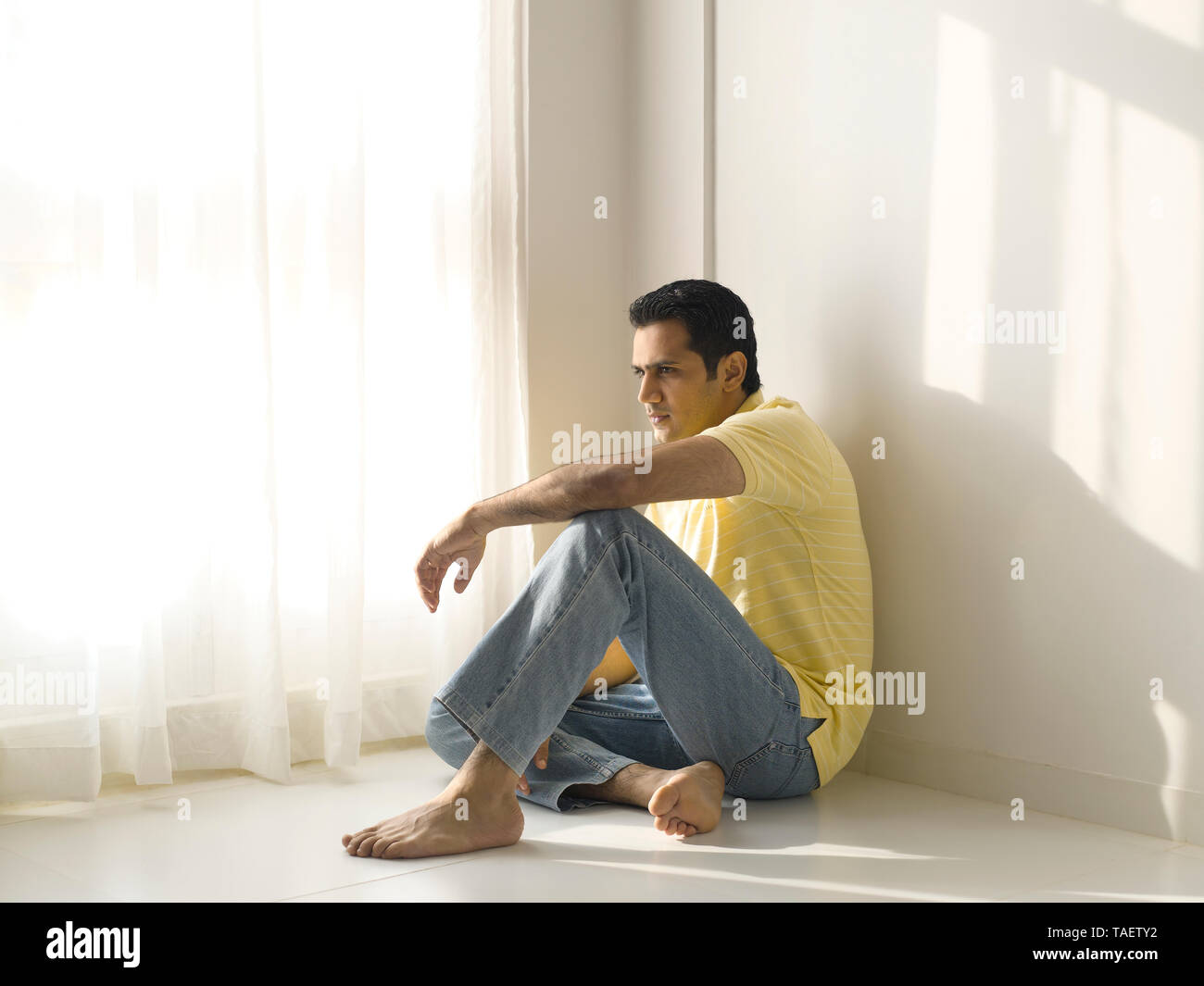 PORTRAIT OF A DEPRESSED MAN SITTING IN HIS HOME Stock Photo