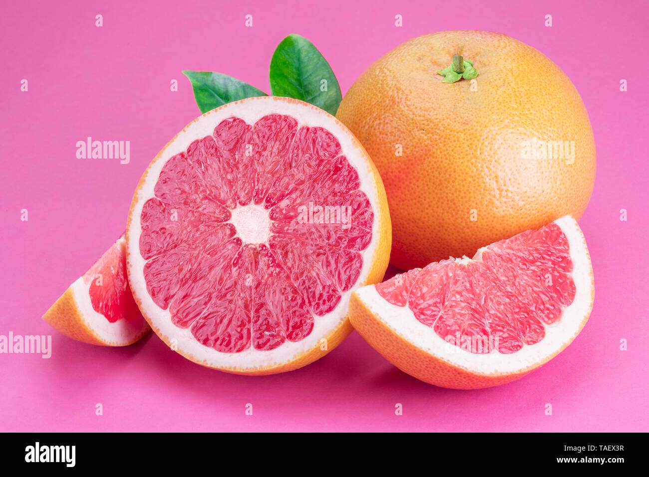 Grapefruit and grapefruit slices isolated on pink background. Stock Photo
