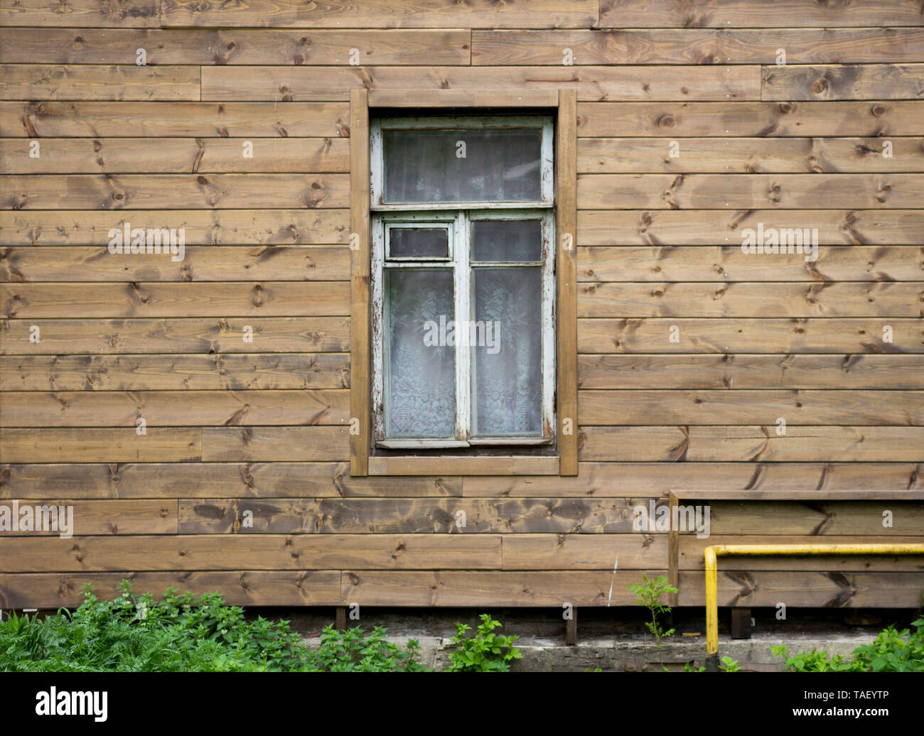 texture of a wooden wall of an old house with a window and frame covered with peeling white paint Stock Photo