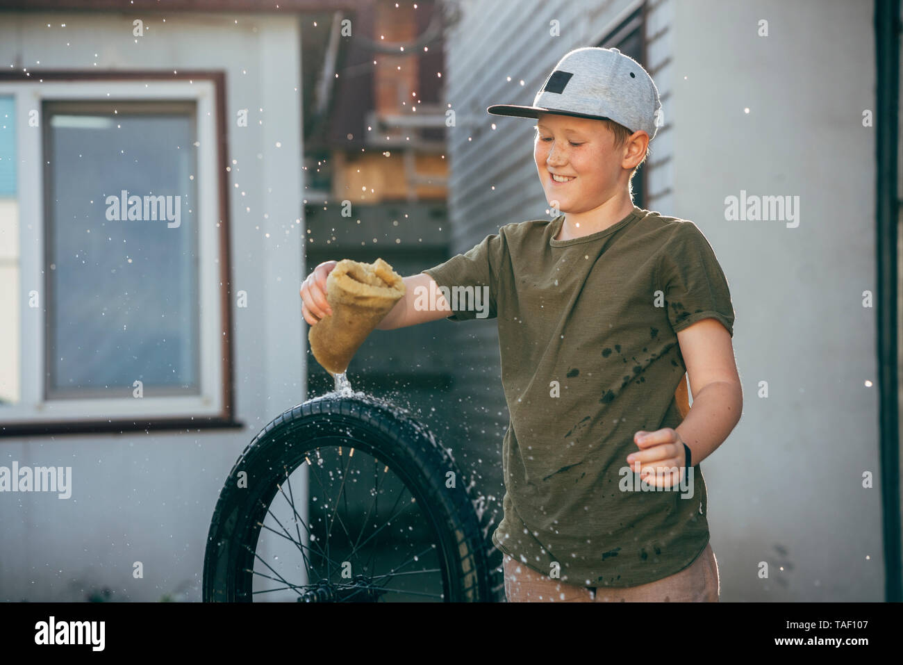 Happy boy cleaning bmx bike on yard Stock Photo