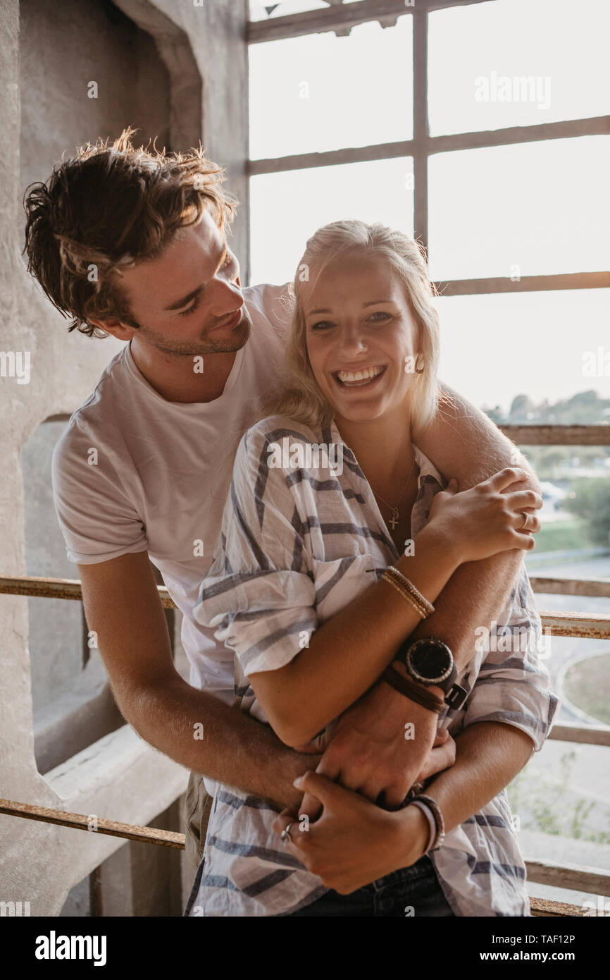 Happy young couple cuddling at the window Stock Photo - Alamy