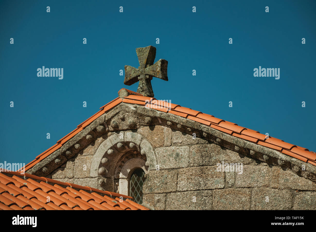 Shingles on roof of medieval chapel with small window and stone cross at Belmonte. Birthplace of the discoverer Pedro Cabral in Portugal. Stock Photo