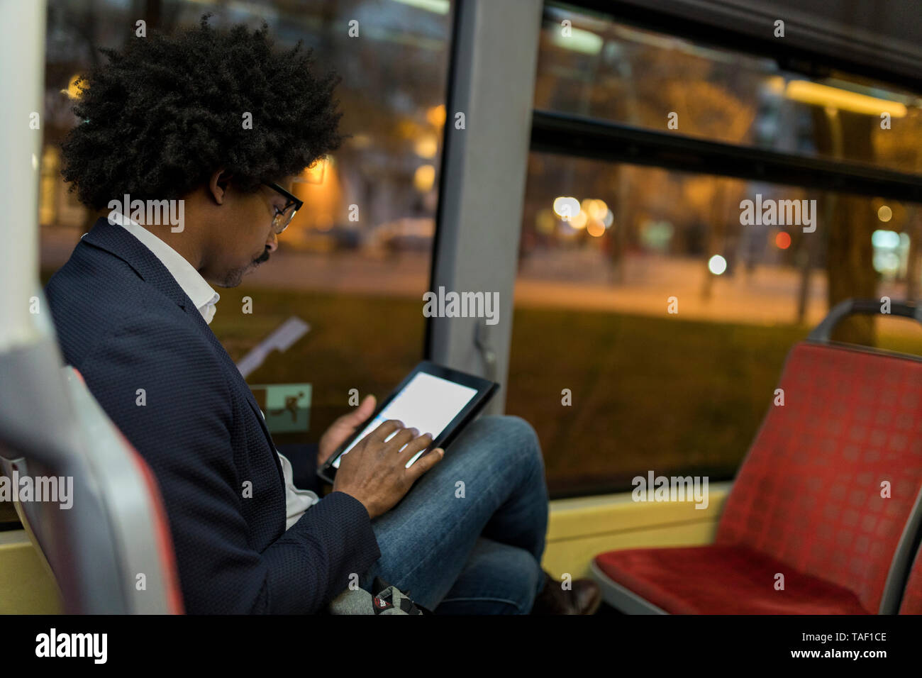 Spain, Barcelona, businessman in a tram at night using tablet Stock Photo