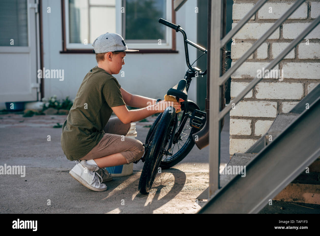 Boy cleaning bmx bike on yard Stock Photo
