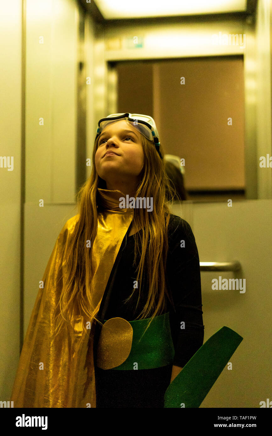 Girl in super heroine costume in elevator looking up Stock Photo