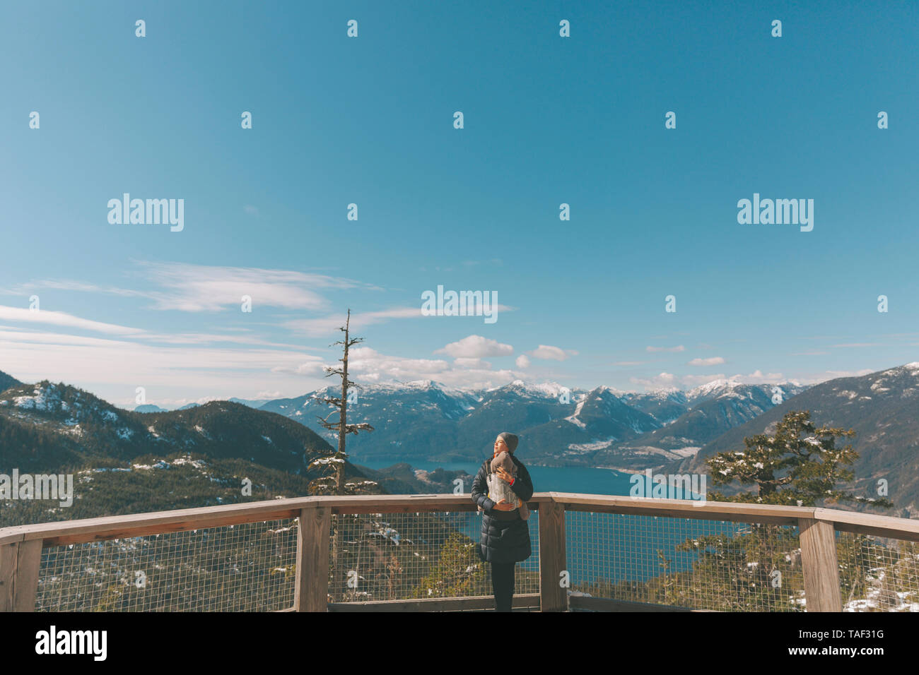Mother holding her baby son on an observation deck, looking over Squamish, Canada Stock Photo