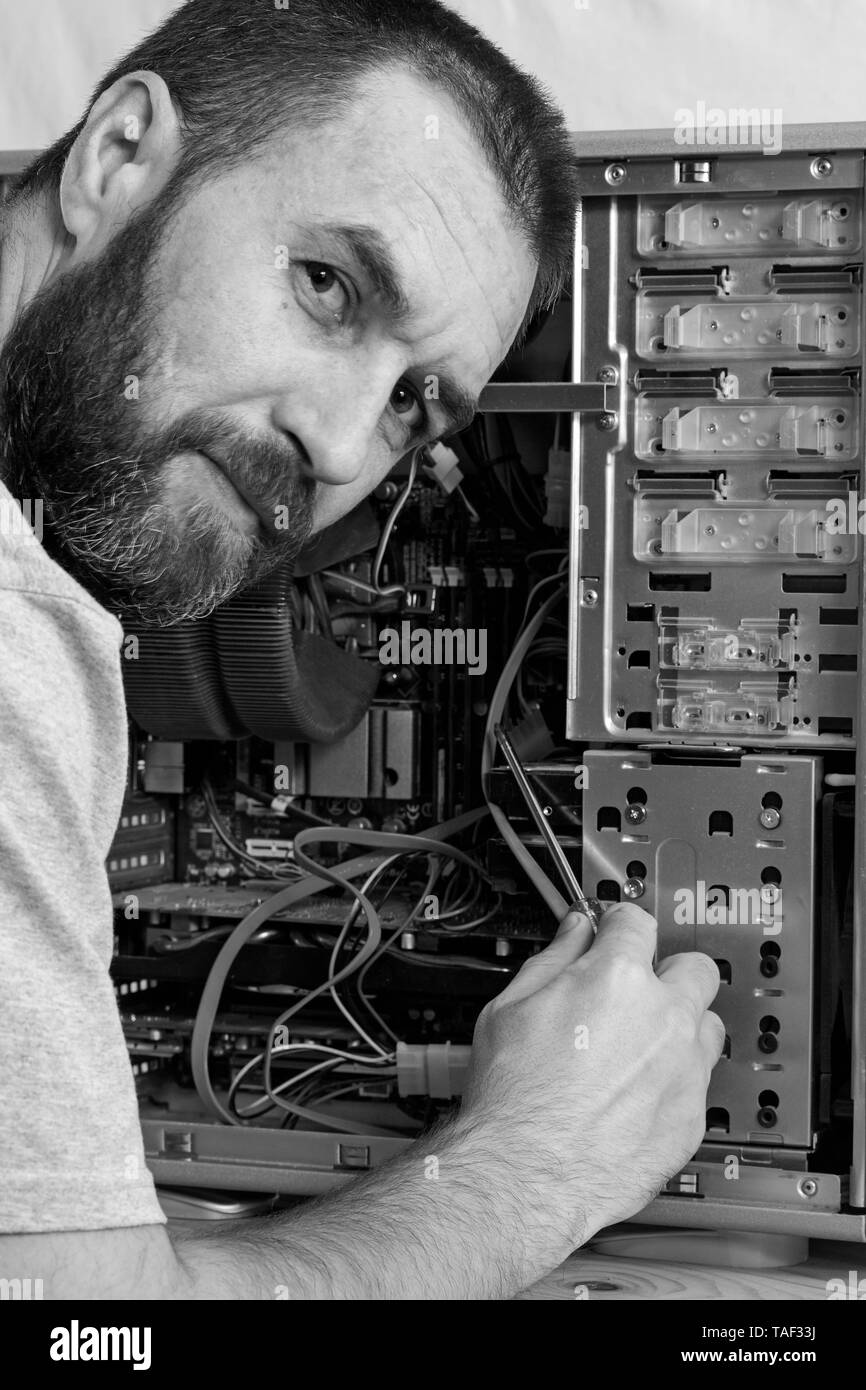 fixing computer. a man with a beard repair the system unit. black and