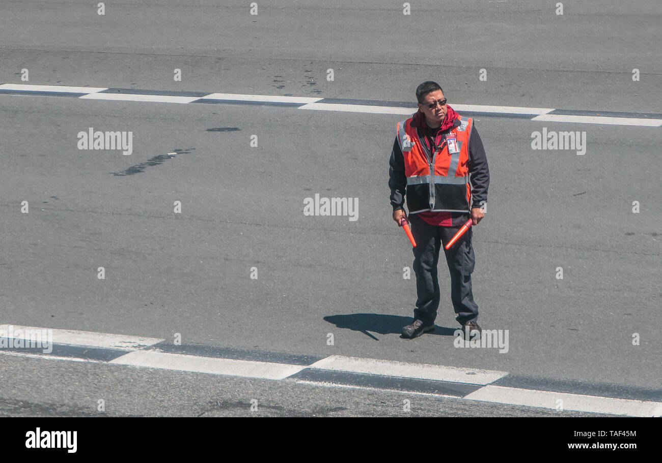 New York, 5/15/2019: Airport ground crew member is guiding a passenger airplane on the runway at LaGuardia airport. Stock Photo