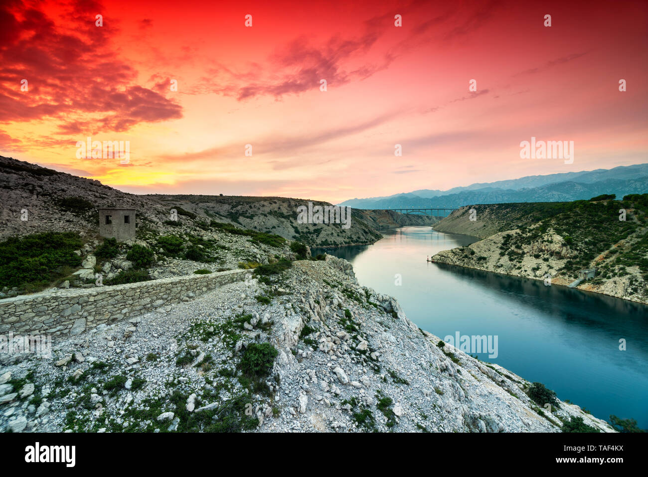 Colorful evening scenic view from Maslenica bridge over the river and mountains with dramatic sunset sky in Dalmatia, Croatia. Wide angle, long exposu Stock Photo