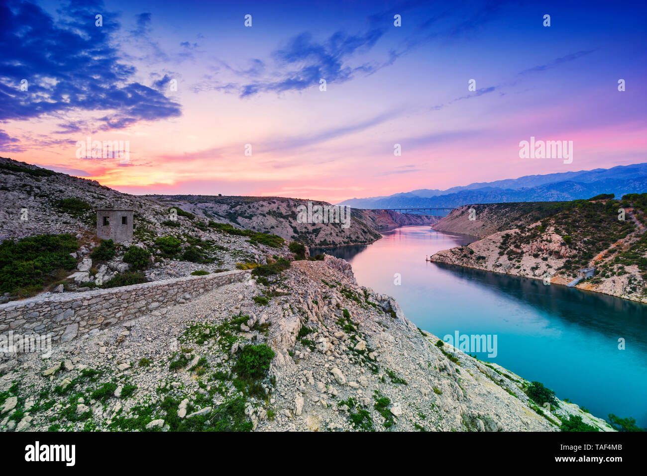 Colorful evening scenic view from Maslenica bridge over the river and mountains with dramatic sunset sky in Dalmatia, Croatia. Wide angle, long exposu Stock Photo