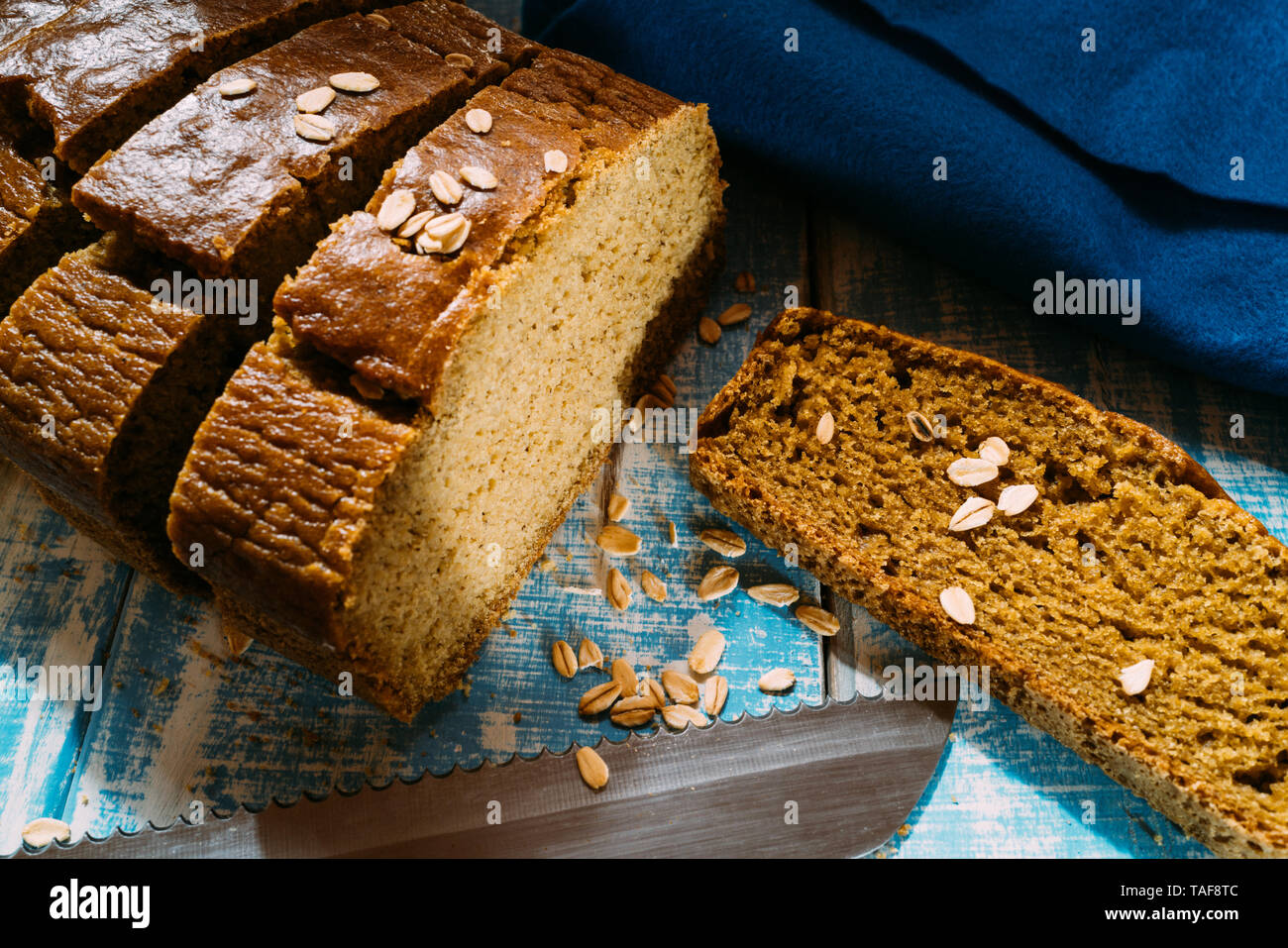 homemade corn bread slices on a blue wooden table with oat flakes Stock Photo