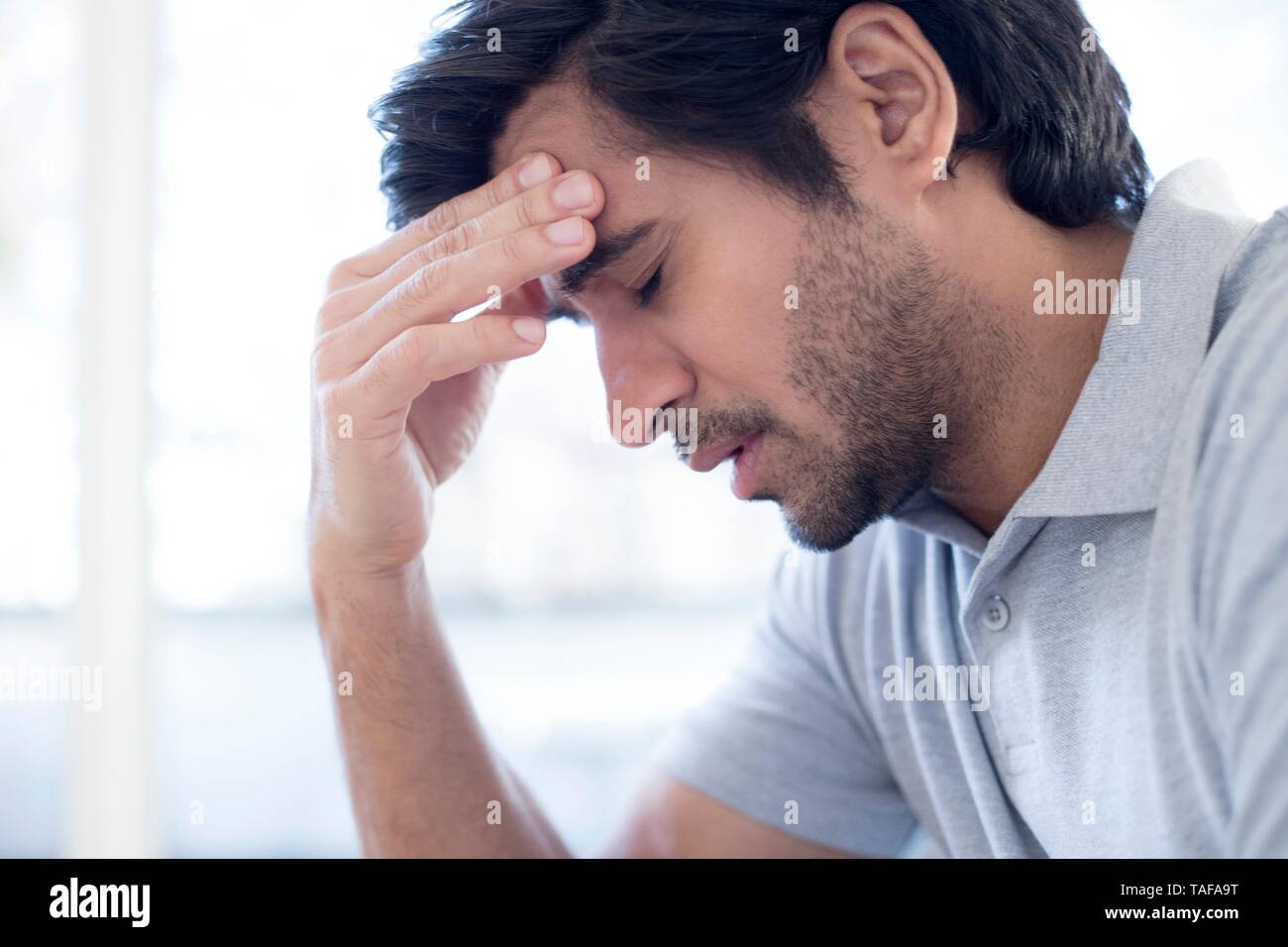 Man touching his forehead in pain Stock Photo