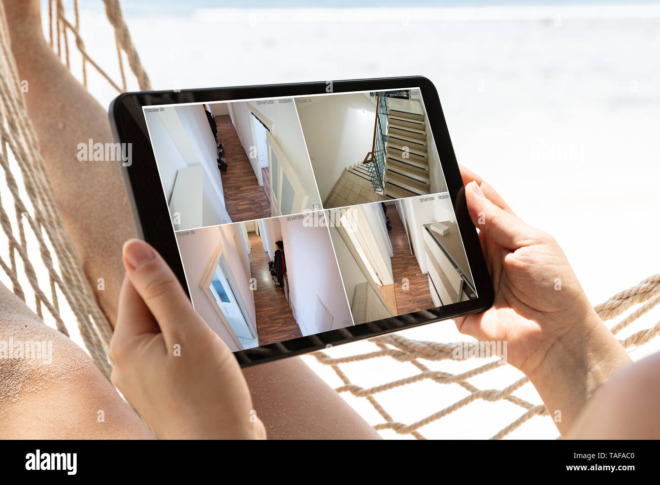 Woman Lying On Hammock Looking At Monitoring Cameras. Live View On The Digital Tablet At Beach Stock Photo