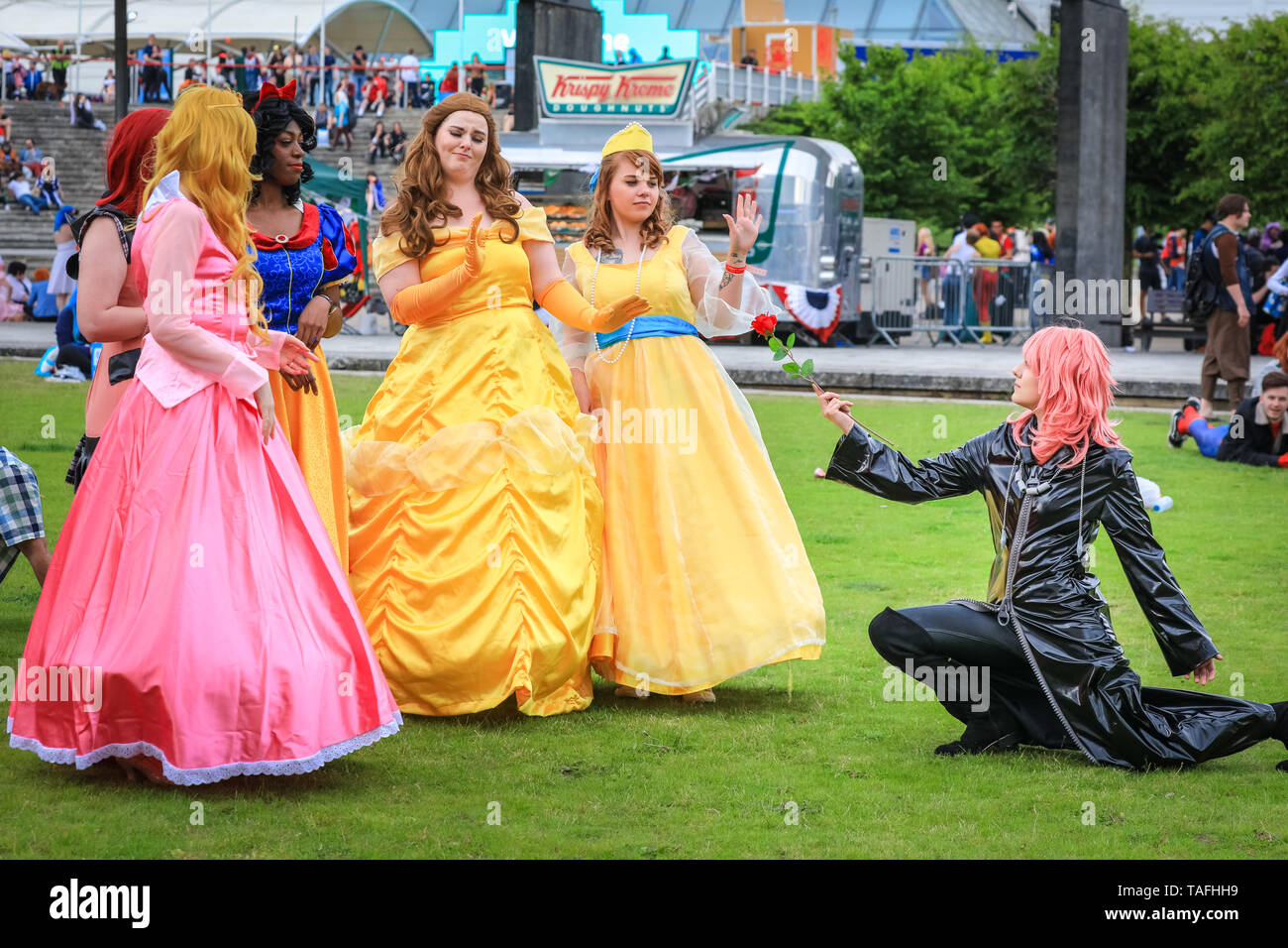 ExCel London, UK - 24th May 2019. Marluxia from Kingdom Hearts presents a rose to a group of Disney princesses and leading ladies, including Cinderella and Sleeping Beauty. Thousands of cosplayers, gamers and lovers of film and TV fantasy and sci fi in costumes come together on the opening day of MCM Comicon at ExCel London. Credit: Imageplotter/Alamy Live News Stock Photo