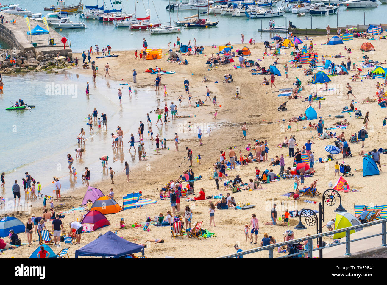 Lyme Regis, Dorset, UK. 25th May 2019. UK Weather: Crowds of holidaymakers and visitors flock to the beach at Lyme Regis to  bask in hot sunshine as the coastal resort sizzles on the hottest day of the year so far. Saturday is set to be the sunniest day of the late May bank holiday weekend.  Credit: Celia McMahon/Alamy Live News. Credit: Celia McMahon/Alamy Live News Stock Photo