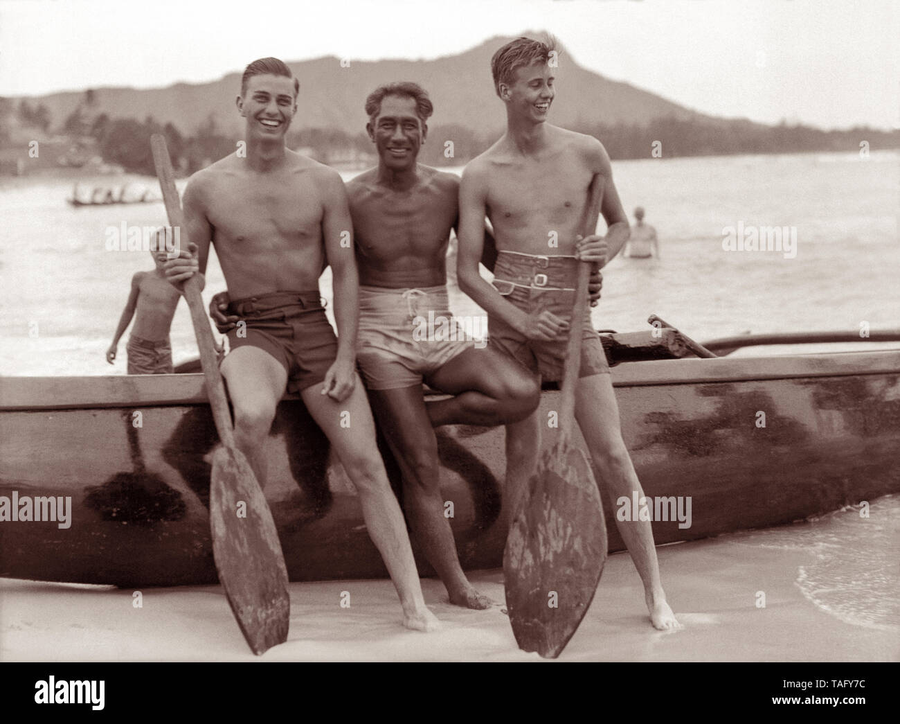 Hawaiian surfing legend, Duke Kahanamoku, with FDR's sons Franklin D. Roosevelt, Jr. and John Roosevelt at Waikiki Beach in Honolulu, Hawaii. President Roosevelt, along with his sons, traveled aboard the USS Houston to Hawaii in 1934, which was the first visit of a sitting US president to the Territory. Duke Kahanamoku gave private surfing lessons to the Roosevelt sons and their party during their stay at Waikiki. Stock Photo