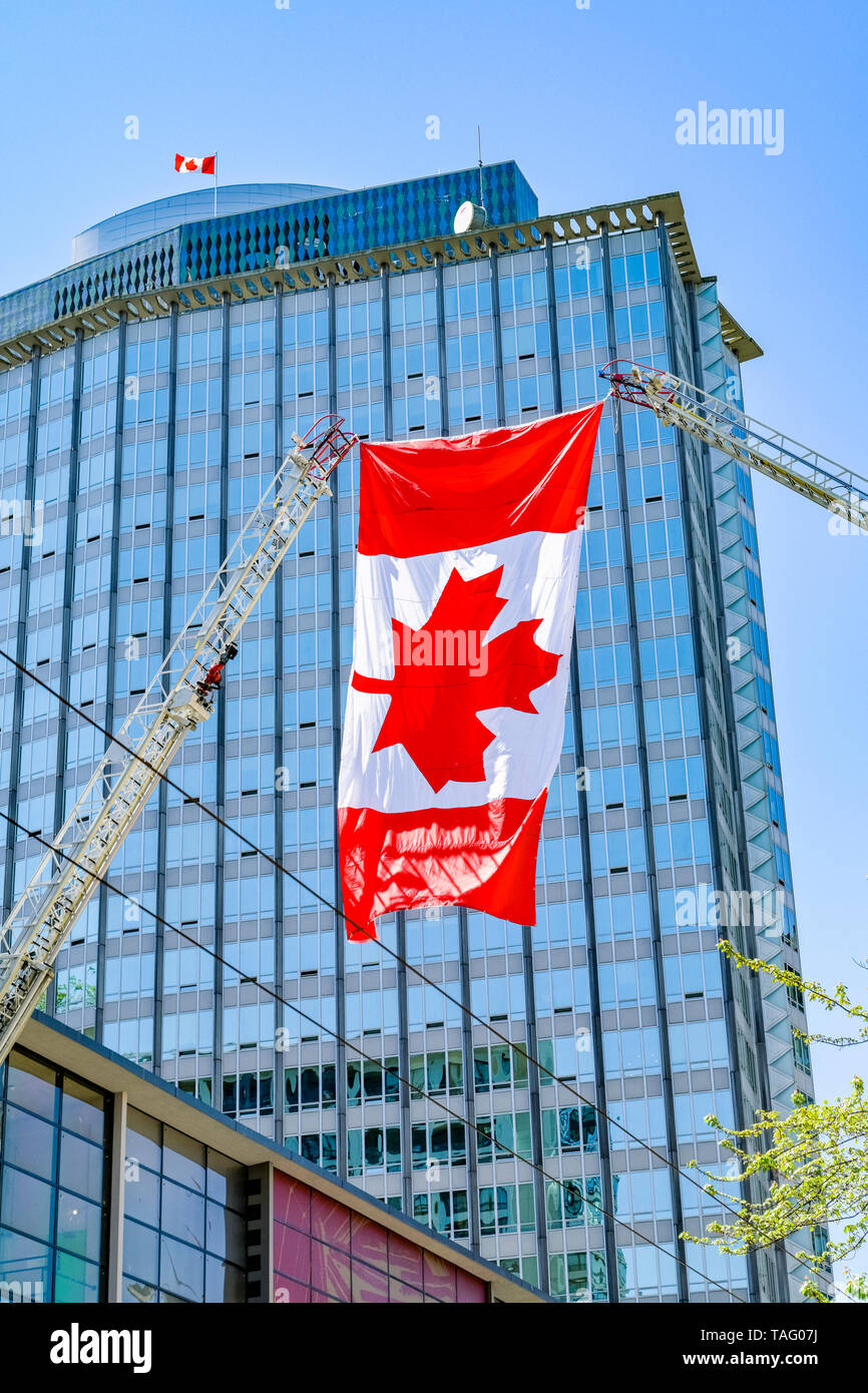 Canadian flag helsd aloft by 2 Fire truck ladders in salute to firefighter who died on duty, Vancouver, British Columbia, Canada Stock Photo