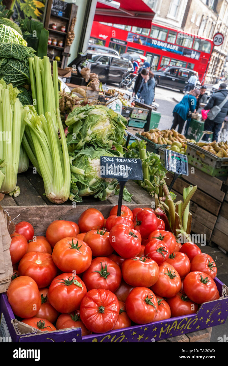 BOROUGH MARKET with Valley Farm Shop stall with farmers attractive rustic vegetable display, red London bus and taxi in background, Southwark London UK Stock Photo