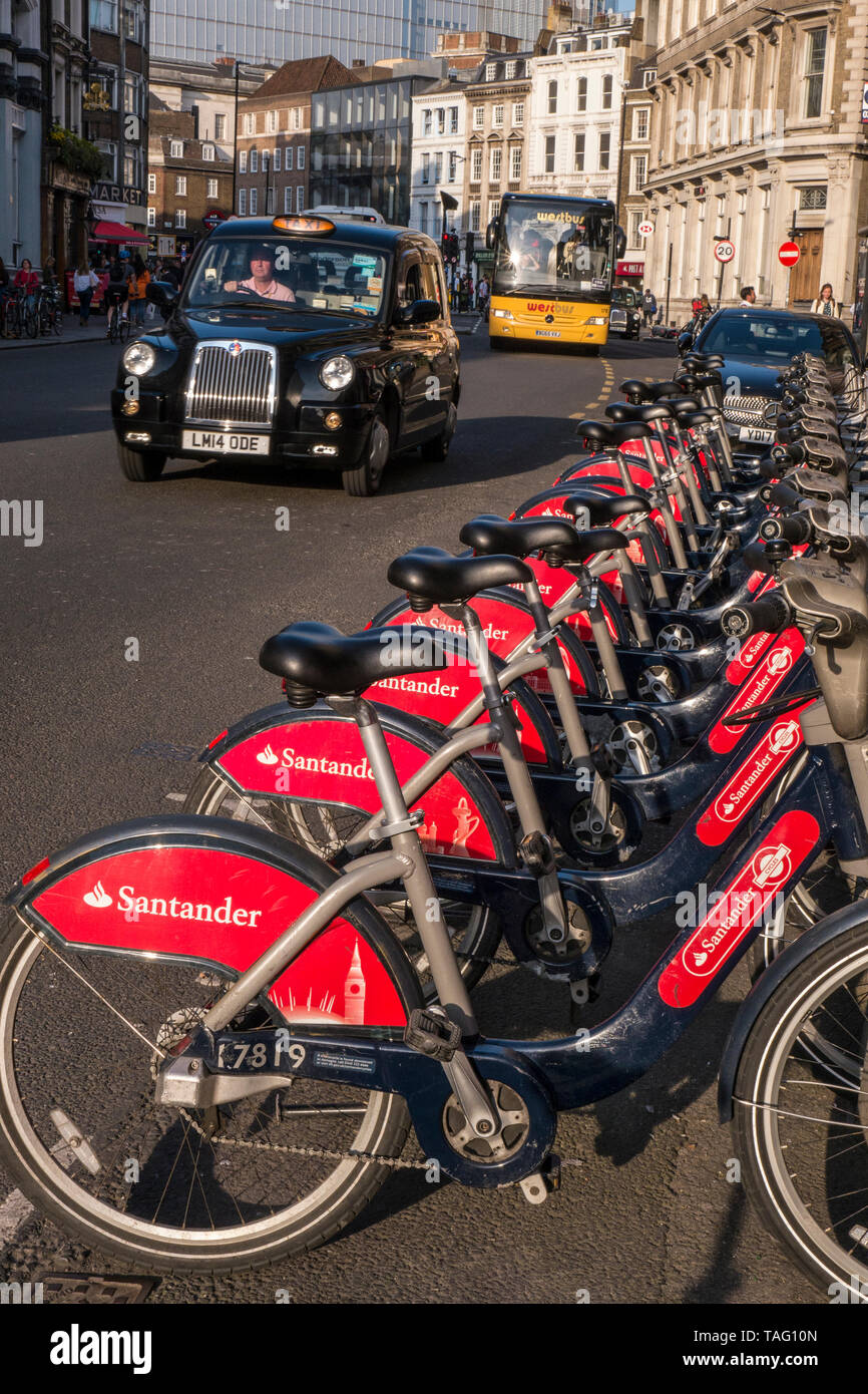 London TFL Santander sponsored line of red rental hire bikes in Southwark Street with London Black Cab behind. Bike terminal docking station. Transport for London Southwark London UK Stock Photo