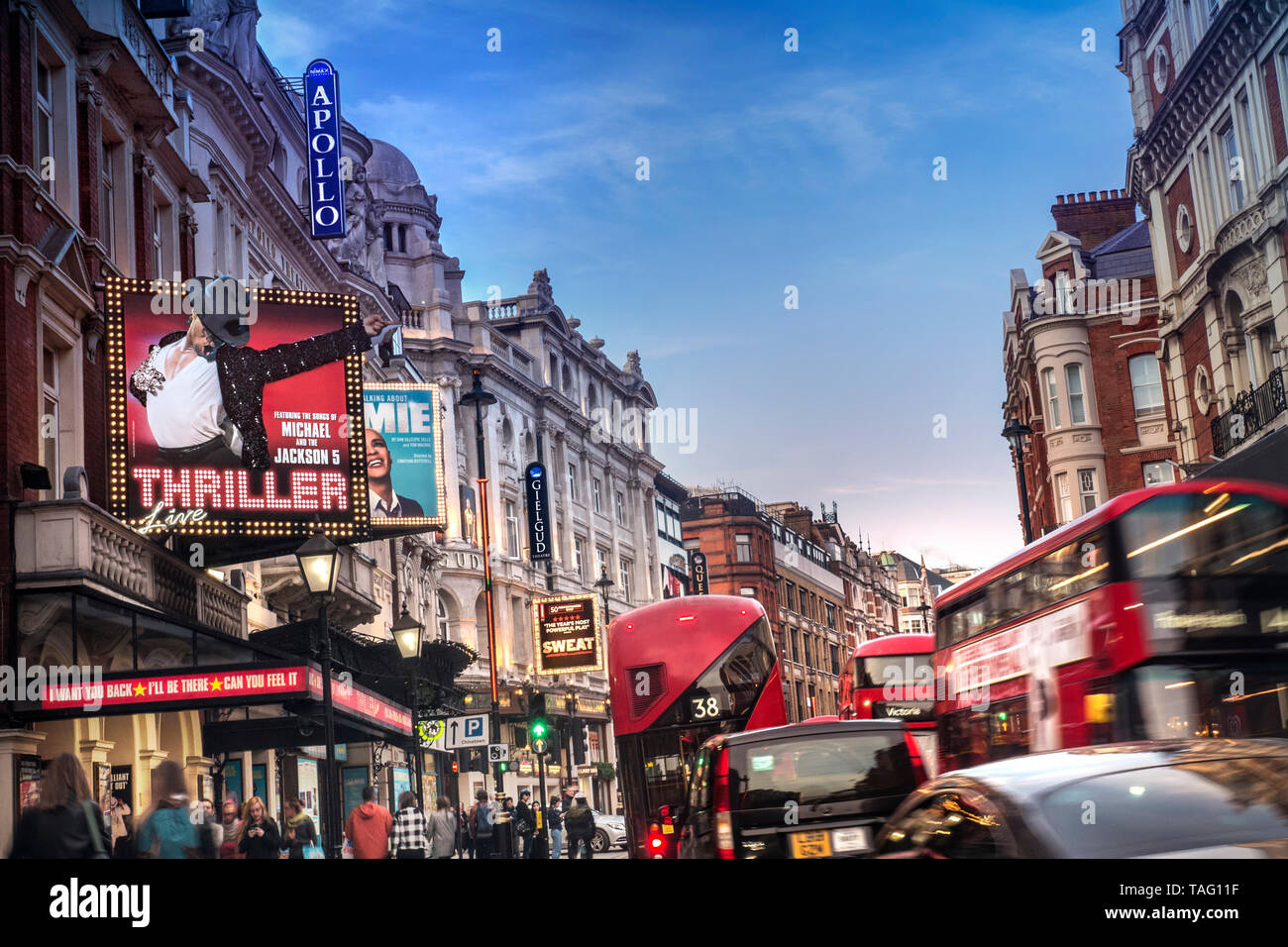 Shaftesbury Avenue London slow traffic jam Theatreland West End theatres busy heavy pollution diesel fumes gridlock with red buses, taxis and people in a busy Shaftesbury Avenue at dusk, with clear blue sky and pollution below. West End London UK Stock Photo