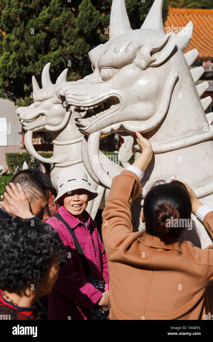 People touch marble dragon for good luck in Buddhist temple Stock Photo