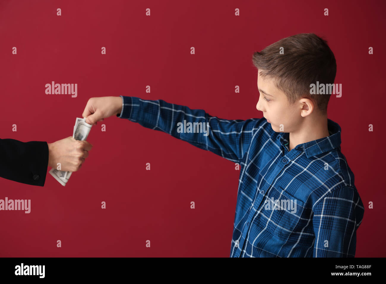 Little boy trying to take money from adult person on color background. Concept of child support Stock Photo