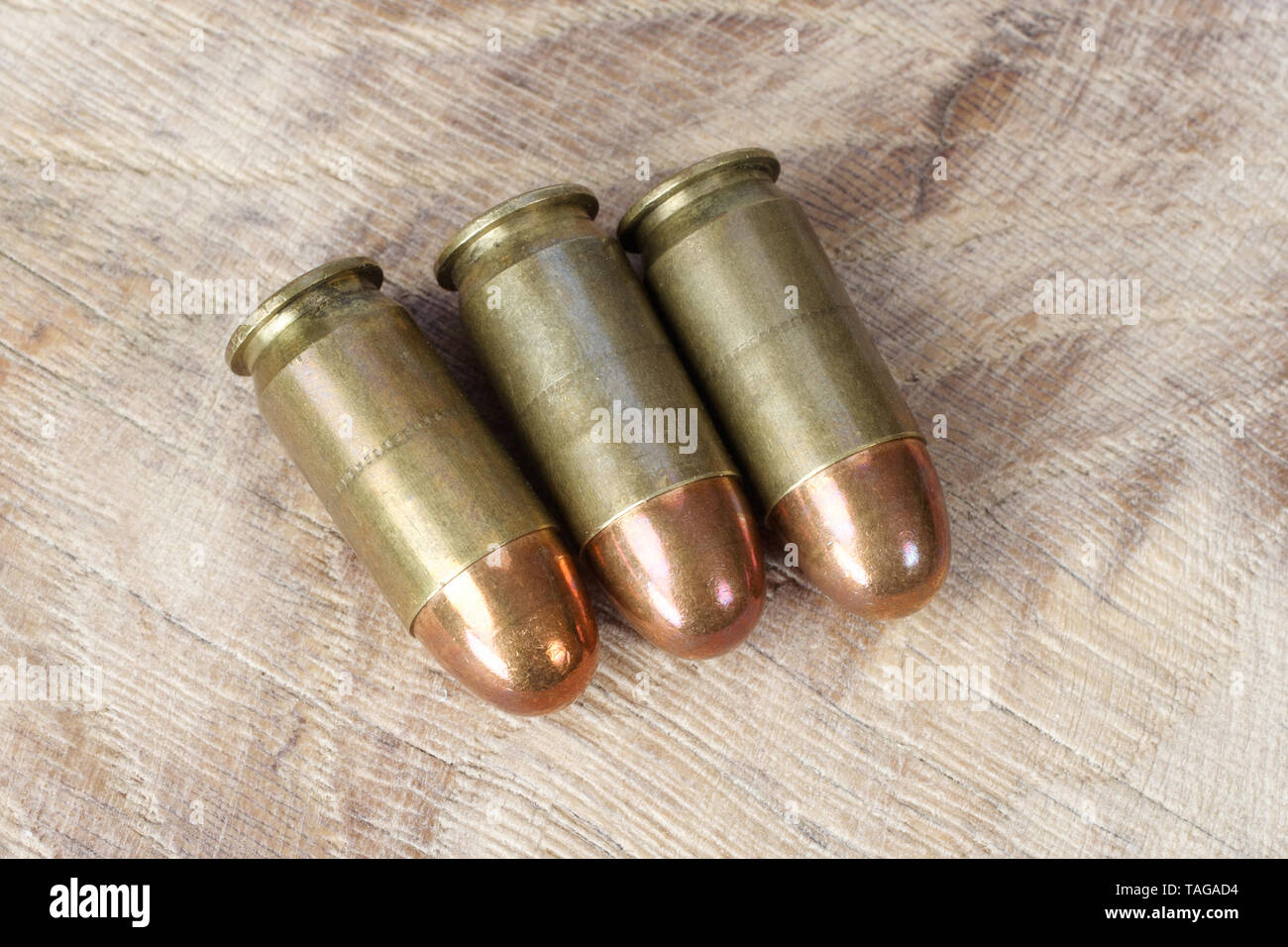 .45 ACP (Automatic Colt Pistol), or .45 Auto (11.43x23mm) a handgun cartridges designed by John Browning in 1905 on wooden background Stock Photo